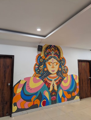 A mural of a deity with elaborate jewelry and a floral headdress on a wall.