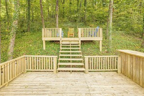 A wooden deck with a central staircase leading to a platform with two chairs. - Deck & Game Room! Modern Lake Guntersville Retreat (Guntersville)