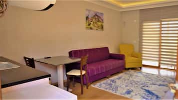 A small living area with a purple sofa, a yellow armchair, a dining table, and a painting on the wall.