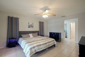 A bedroom with a bed, a ceiling fan, a dresser, and a door leading to another room. - Canal-Front Home w/ Boat Lift & Pool in Cape Coral (Cape Coral)