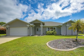 A two-story house with a garage, a front porch, and a well-maintained lawn. - Canal-Front Home w/ Boat Lift & Pool in Cape Coral (Cape Coral)