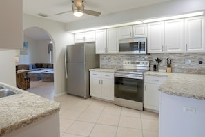A modern kitchen with stainless steel appliances, white cabinetry, and a tiled backsplash. - Canal-Front Home w/ Boat Lift & Pool in Cape Coral (Cape Coral)
