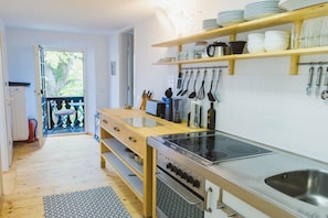 A kitchen with wooden shelves, a stove, and a sink. - Holiday apartment with 2 bedrooms (Utting)