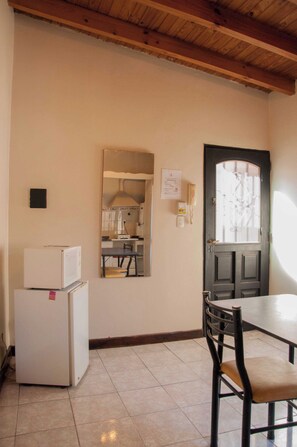 A kitchen with a refrigerator, a sink, and a mirror. There is a door with a window and a light switch on the wall. - Wine Aparts (Mendoza)