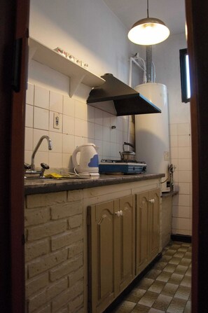 A kitchen with a tiled backsplash, a gas stove, a kettle, and a sink. - Wine Aparts (Mendoza)