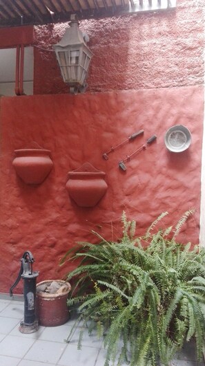 A red wall with three terracotta pots, a lantern, and a small metal dish. - Wine Aparts (Mendoza)