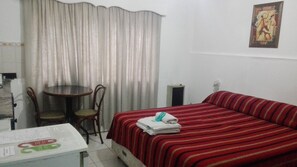 A room with a bed, a table, chairs, a curtain, and a poster on the wall. - Wine Aparts (Mendoza)
