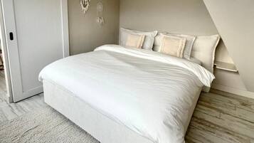 Een slaapkamer met een bed, een aan de muur bevestigde dromenvanger en een houten vloer.