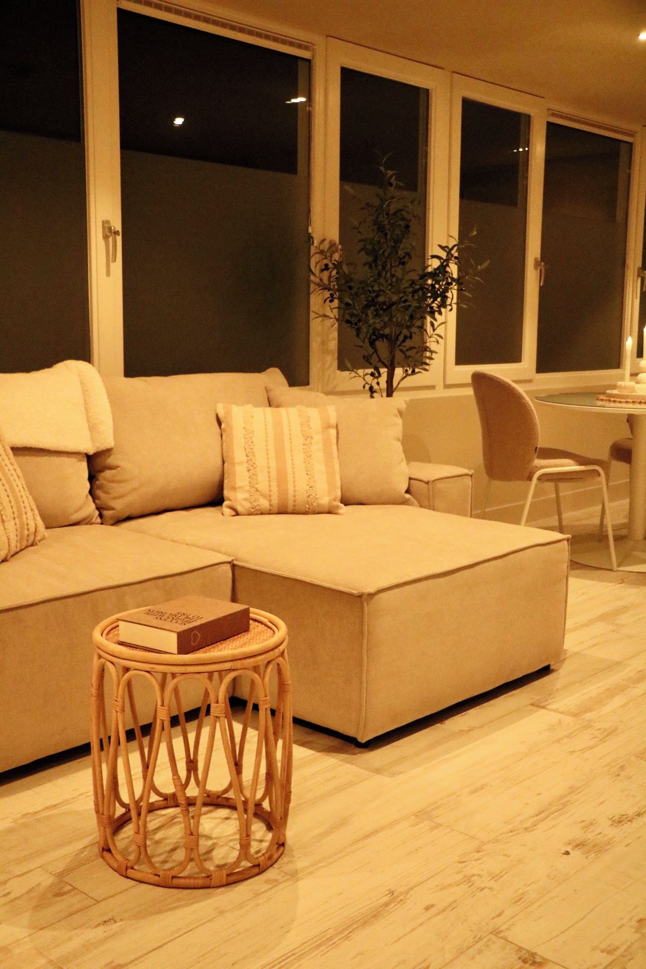 Un salon moderne avec un canapé d’angle, une petite table ronde et une plante en pot.