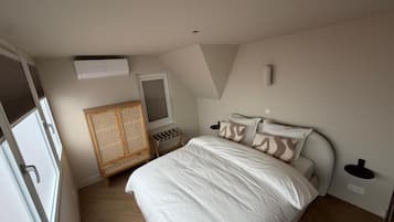 A bedroom with a bed, a wardrobe, a window, and a ceiling light.