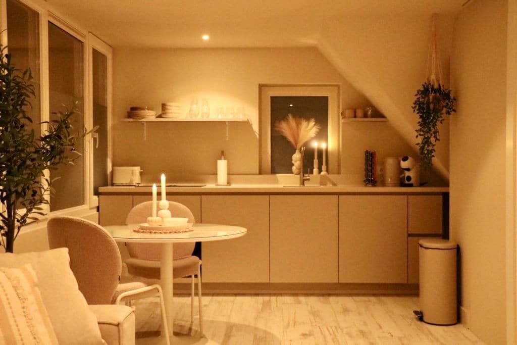 A compact kitchen with a dining area, a small island, and a trash bin.