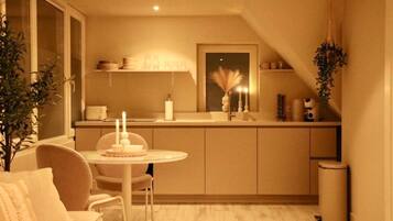 A compact kitchen with a dining area, a small island, and a trash bin.
