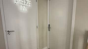 A hallway with a sign reading 'BREEZE INN' on a door, wooden flooring, and white walls.