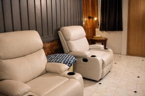 Una habitación con sillón de masaje, una pequeña mesa con lámpara y pared de ladrillo.