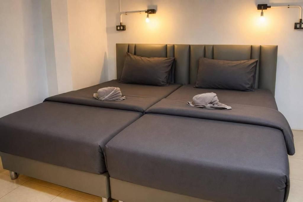 Cama doble con cabecera gris y dos lámparas de noche.