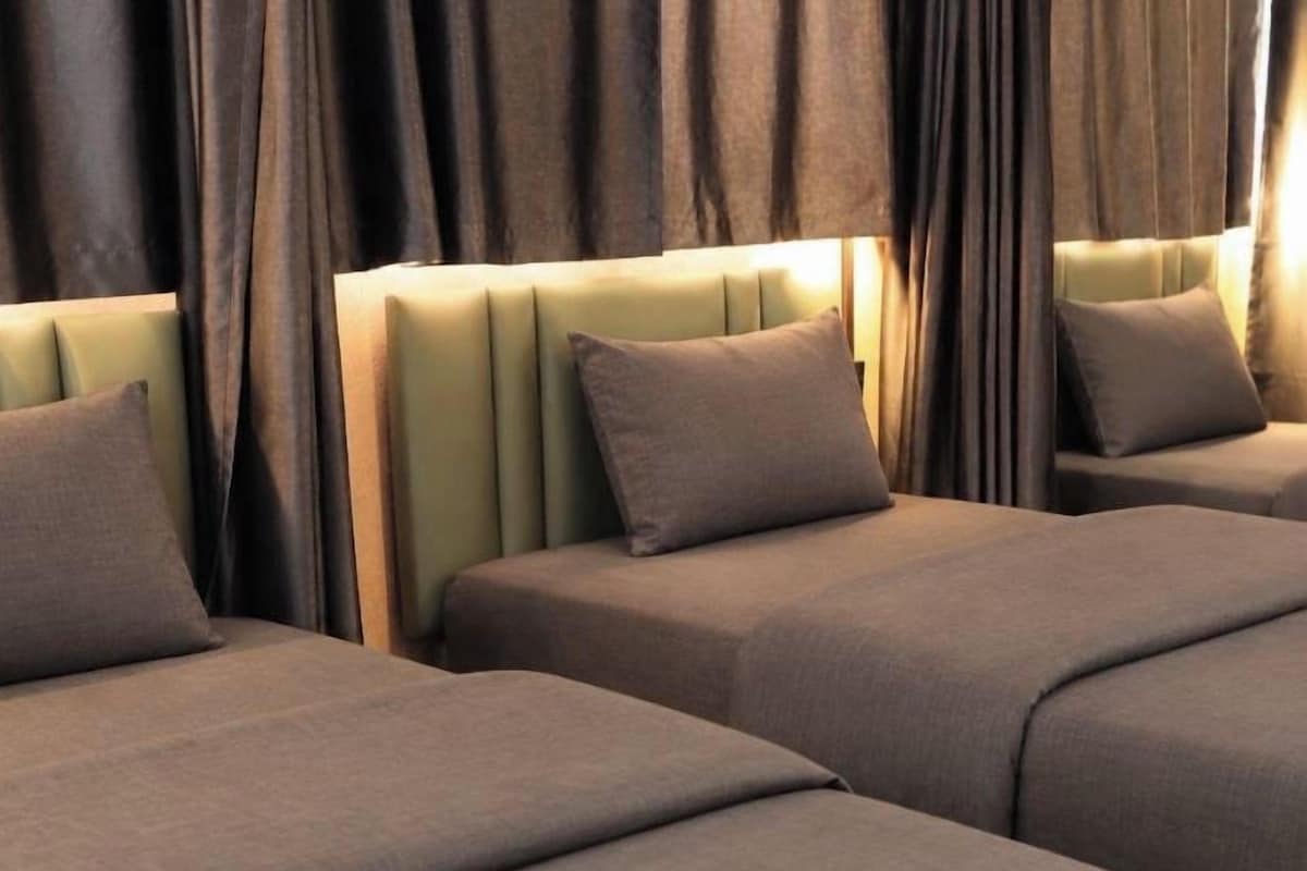 A hotel room with three beds, each with a headboard and pillows.