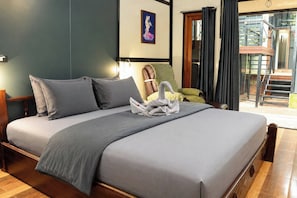 A hotel room with a bed, pillows, a towel arrangement, a painting, and a view of the outside.