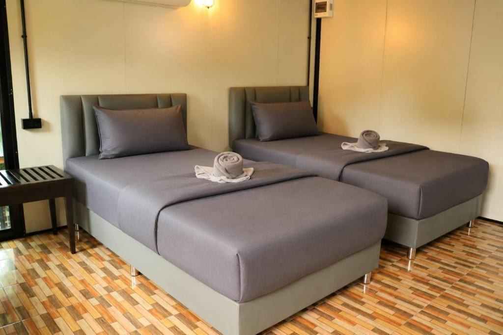 A hotel room with two beds, a small table, and a patterned floor.