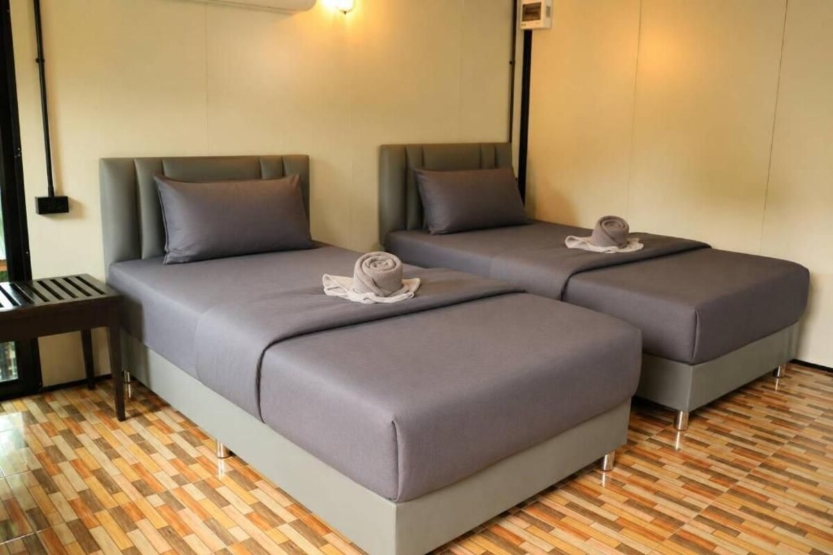 A hotel room with two beds, a small table, and a patterned floor.