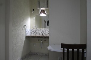 Baño con lavamanos blanco, espejo y ventilador de techo.