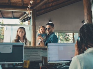 Una recepción con computadoras, un teléfono y un cartel que muestra las tarifas de las habitaciones.