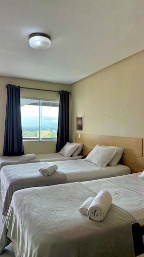 Habitació d'hotel amb dos llits, vista a les muntanyes i una làmpada al sostre.