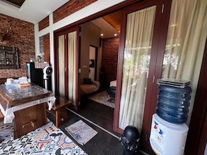 Una habitación con una mesa de madera, un dispensador de agua y una alfombra estampada.
