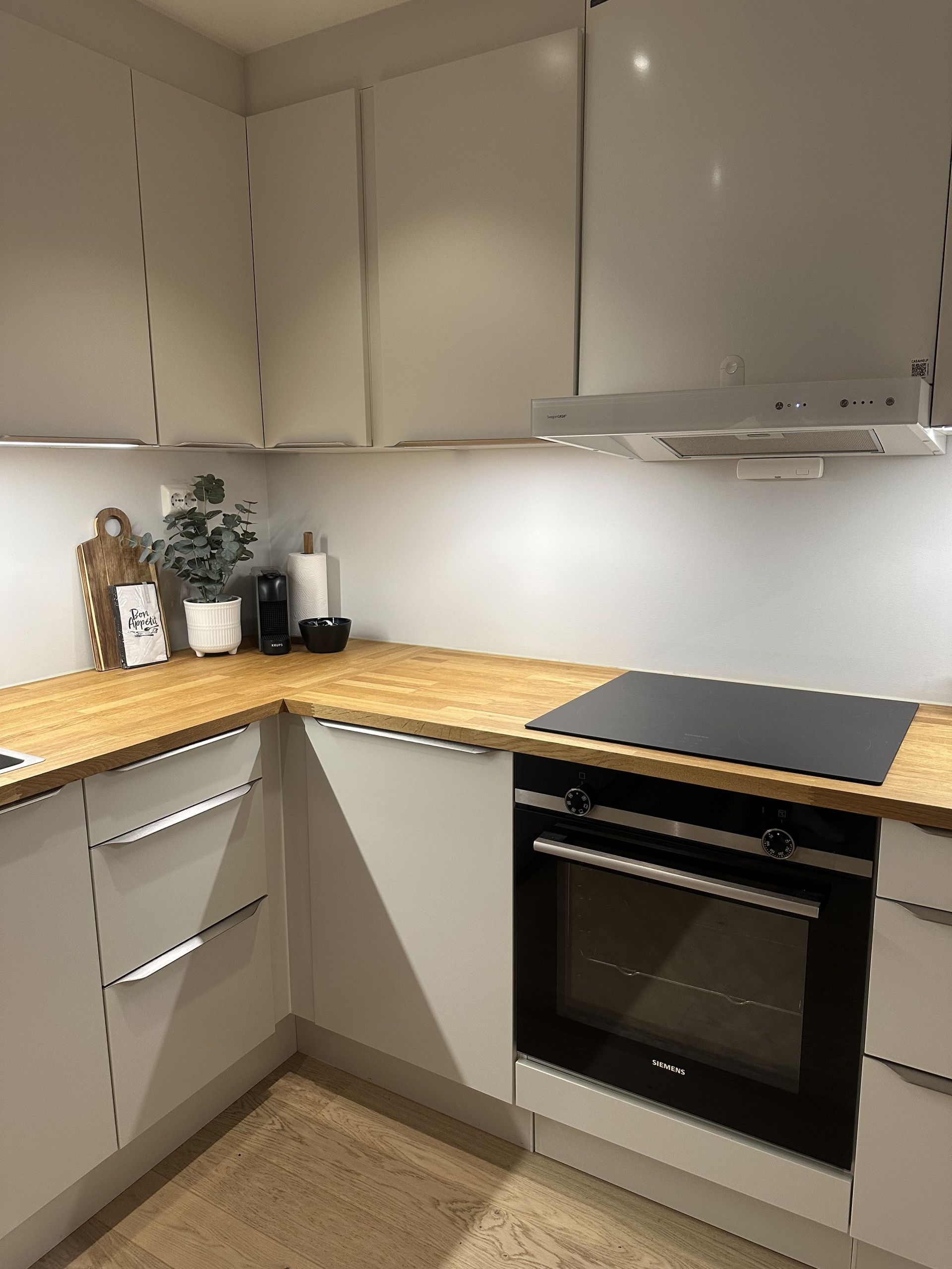 Una cocina con horno integrado, microondas y extractor.