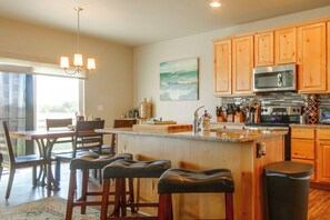 A modern kitchen with wooden cabinets, a stainless steel oven, and a bar area with stools. - Family-Friendly Home! Walk to Windsor Lake (Windsor)