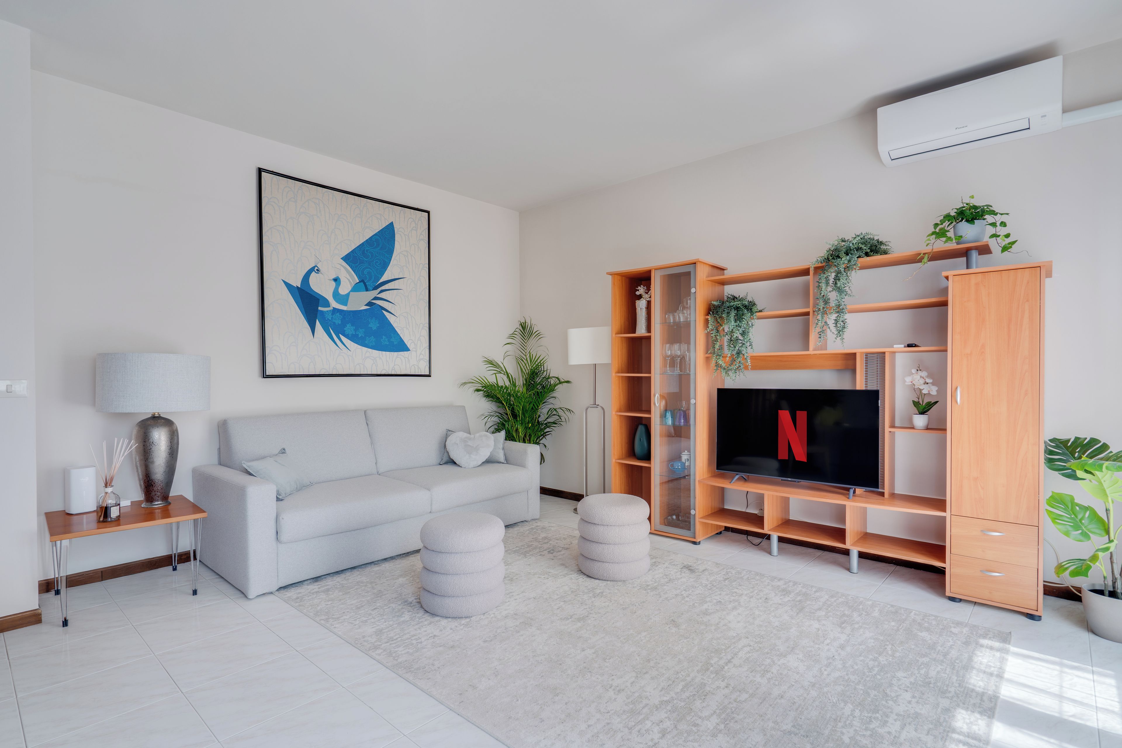 Un soggiorno moderno con un divano grigio, una TV a schermo piatto e un mobile porta TV in legno con piante.