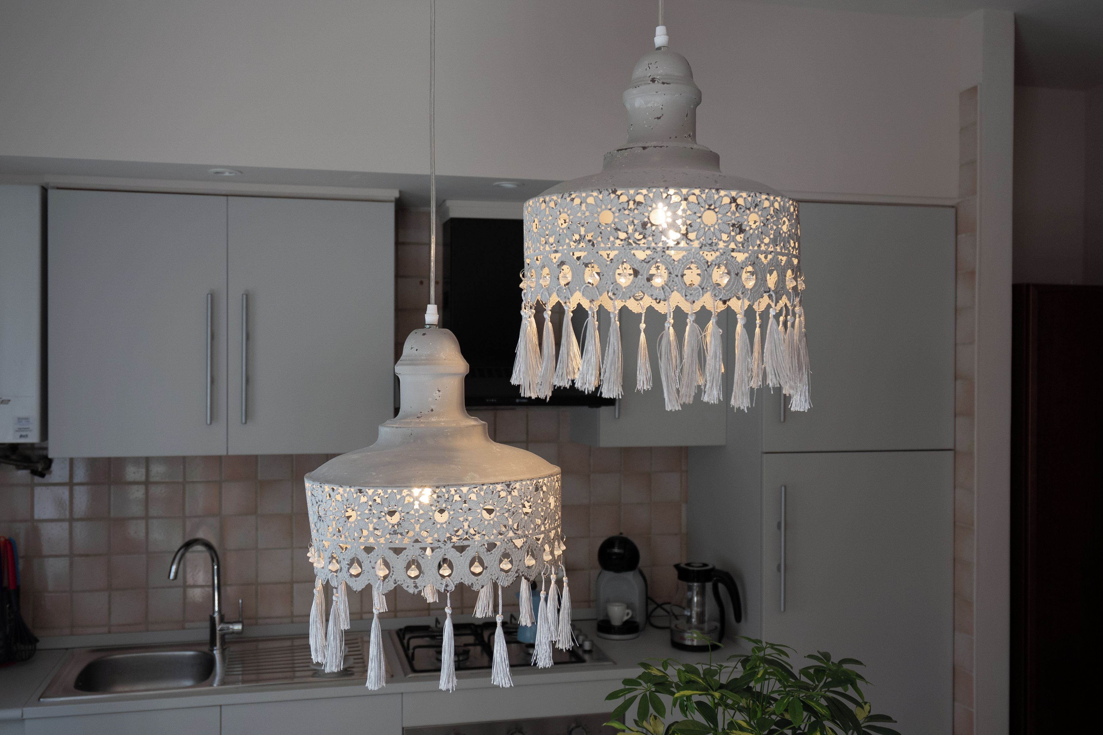 Una cucina con mobili bianchi, un lavello e un lampadario decorativo.