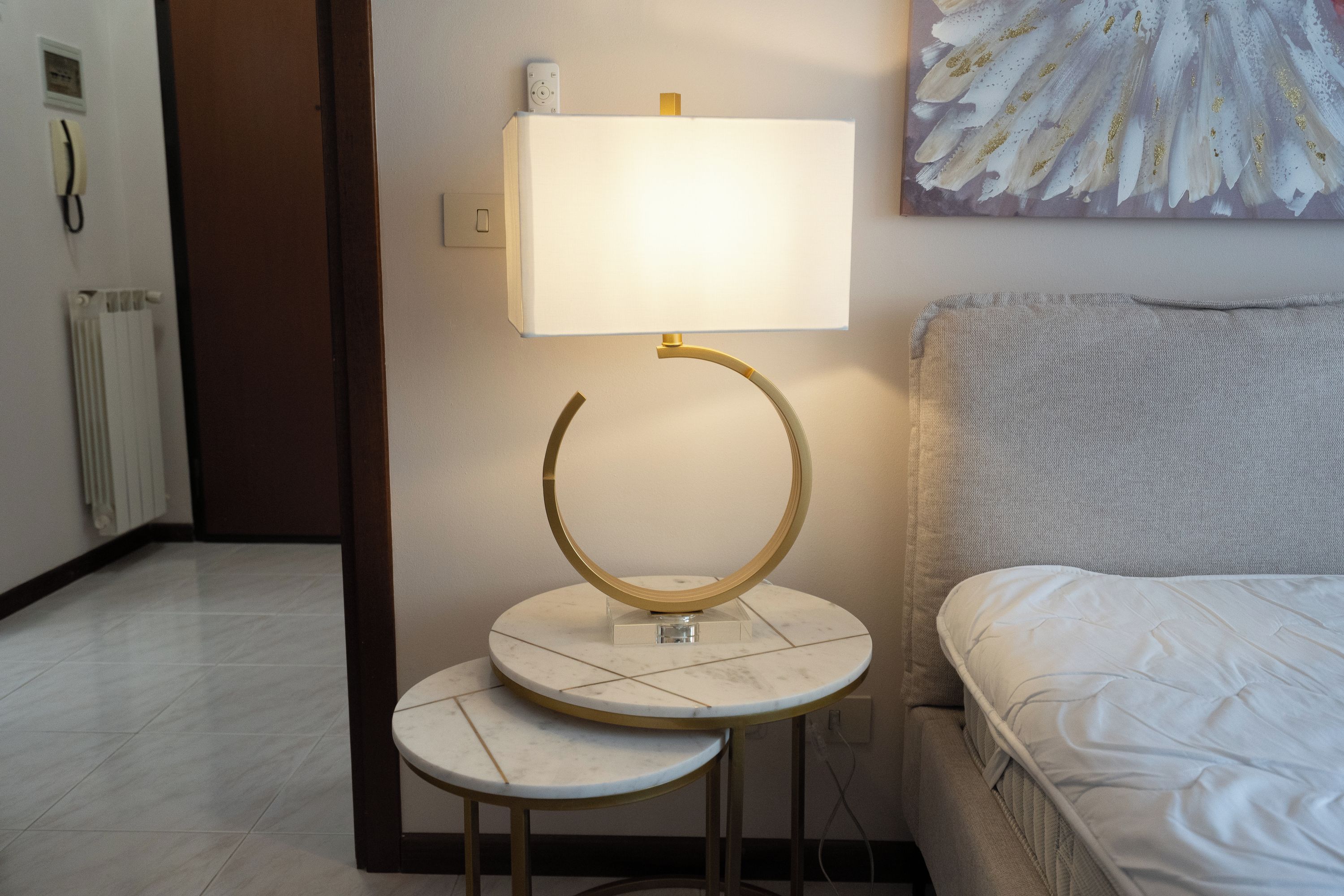 Habitación de hotel con una cama, una mesita de noche con lámpara y un cuadro en la pared.