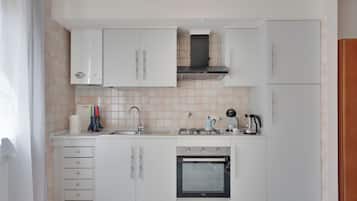 Una cucina moderna con mobili bianchi, un lavello in acciaio inossidabile, un piano cottura a gas e un forno integrato.