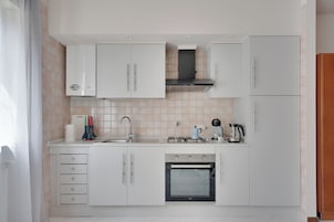A modern kitchen with white cabinets, a stainless steel sink, a gas stove, and a built-in oven.