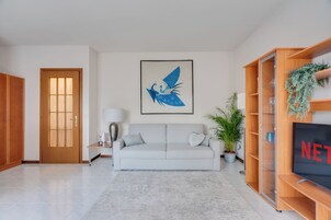 Una sala de estar con un sofá, un televisor, una puerta y un cuadro colgado en la pared.
