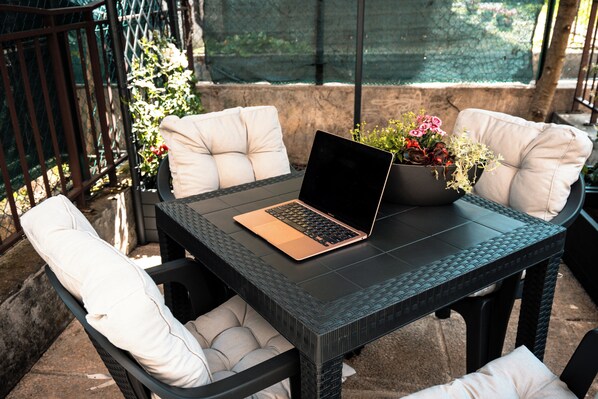 A table with a laptop, surrounded by cushioned chairs, with a potted plant on the table.