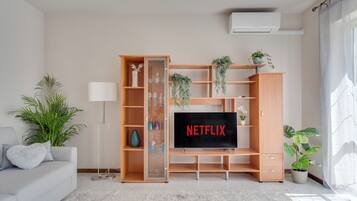A living room with a wooden entertainment unit, a flat-screen TV, and a potted plant.