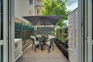 Un patio con una mesa, sillas, un paraguas grande y una planta en maceta.