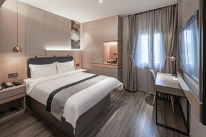 Ein modernes Hotelzimmer mit einem großen Bett, einem Nachttisch und einem Schreibtisch mit Stuhl.