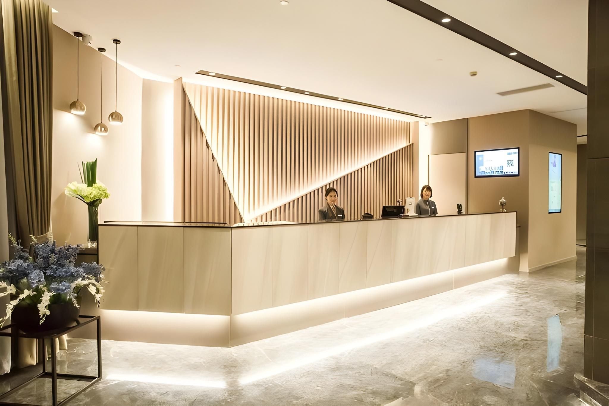 A reception desk with a modern design, a flat-screen TV, and a digital display.