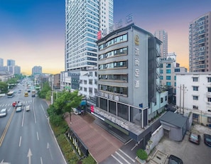 Un moderno edificio de hotel con varios pisos, grandes ventanales y un letrero llamativo.