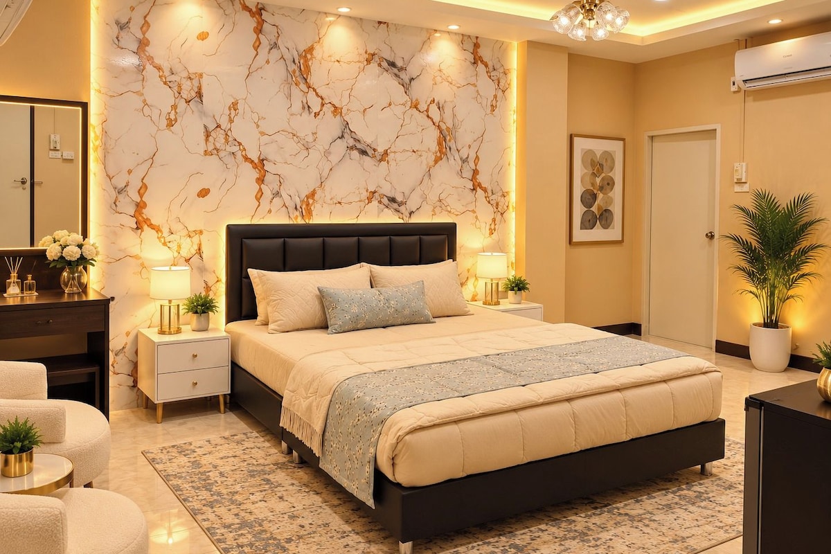 Un dormitorio moderno con pared con diseño de mármol, una cama grande, lámparas de noche, un ventilador de techo y una planta en maceta.