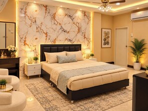 A modern bedroom with a marble-patterned wall, a large bed, bedside lamps, a ceiling fan, and a potted plant. - Jomtien Beach Stay (Pattaya)