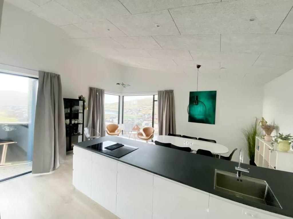 Una cocina moderna con una isla central, una zona de comedor con sillas y un ventanal con vistas.