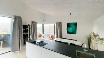 Una cocina moderna con una isla central, una zona de comedor con sillas y un ventanal con vistas.