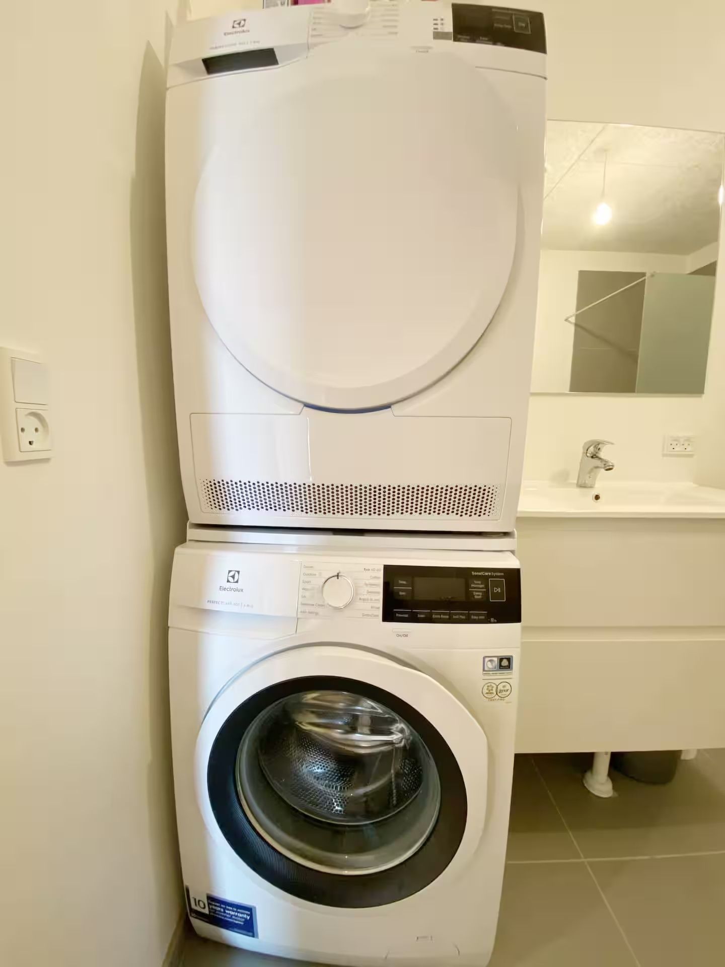 Lavadora y secadora de carga frontal apiladas en un cuarto de servicio.