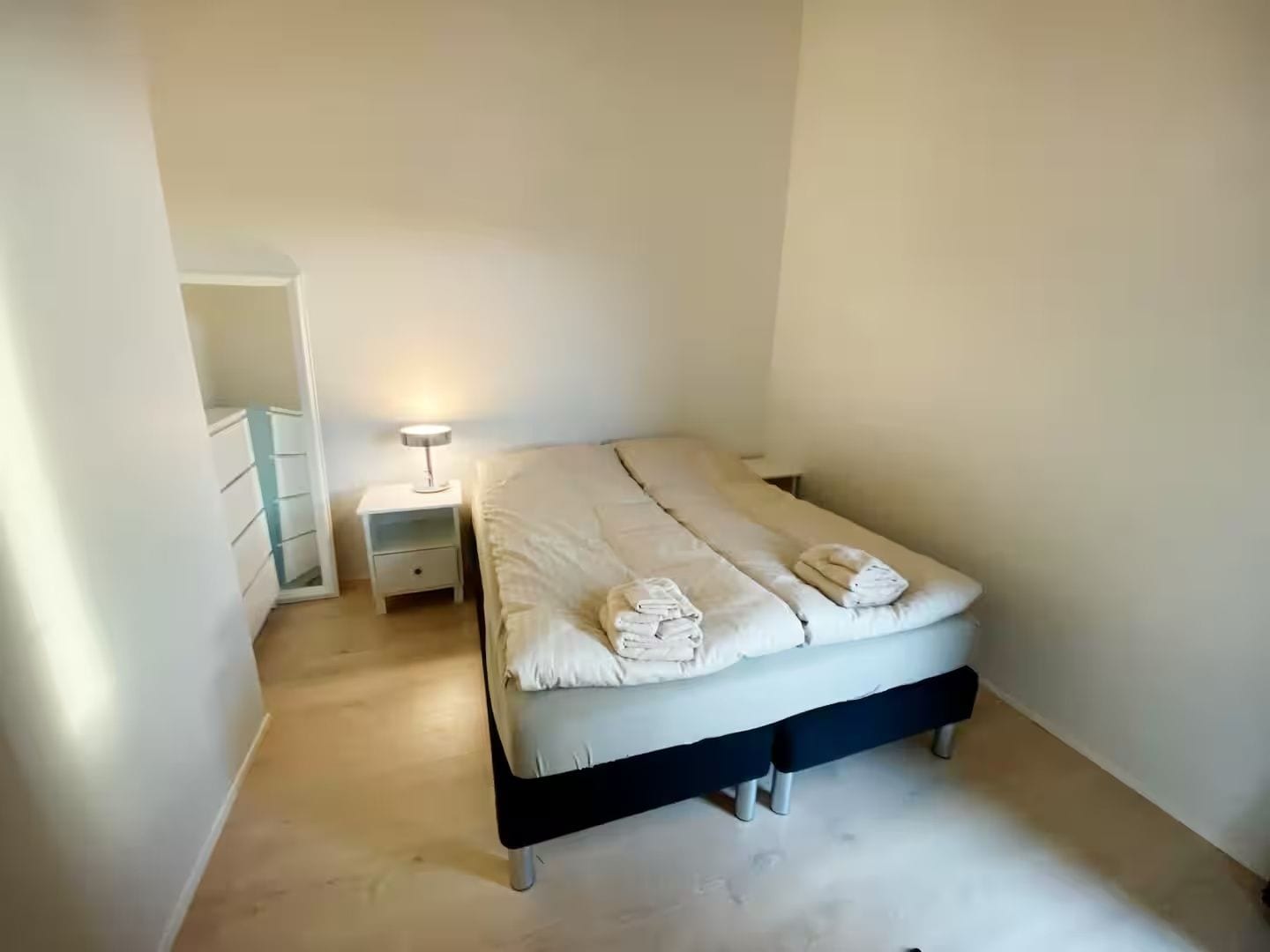 Un dormitorio con cama, mesita de noche y velador.