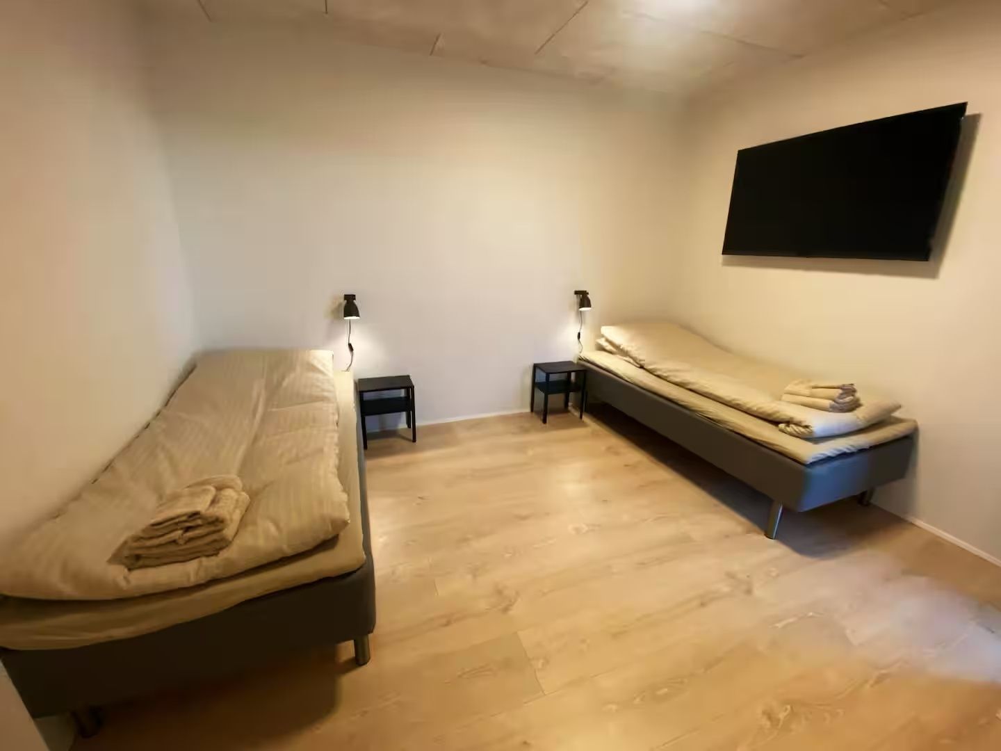Un dormitorio con dos camas, un televisor de pared y lámparas de noche.