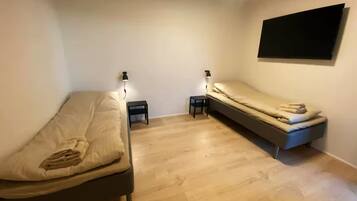 Un dormitorio con dos camas, un televisor de pared y lámparas de noche.
