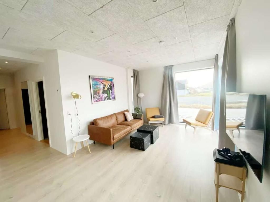 A modern living room with a brown sofa, a small round table, and a flat-screen TV.